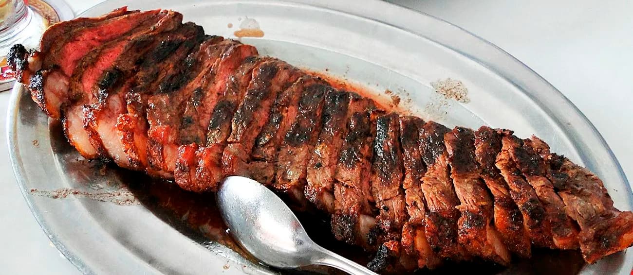 Sliced picanha on a metal platter at Braseiro da Gávea