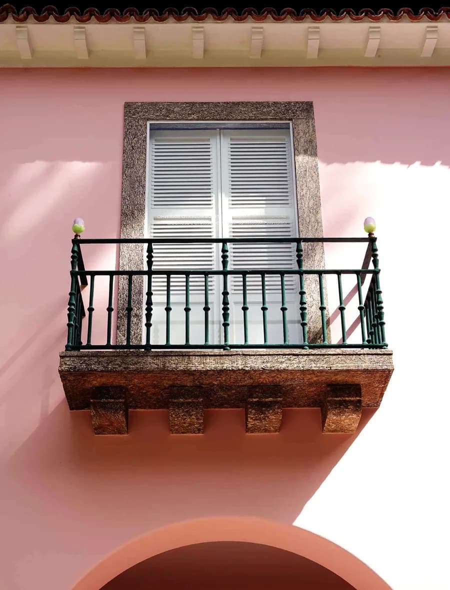 The pink facade and balcony of Casa Roberto Marinho framed by tropical plants