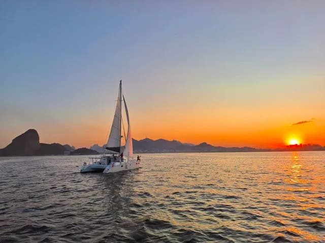 A Velas do Rio catamaran sailing across Guanabara Bay at sunset